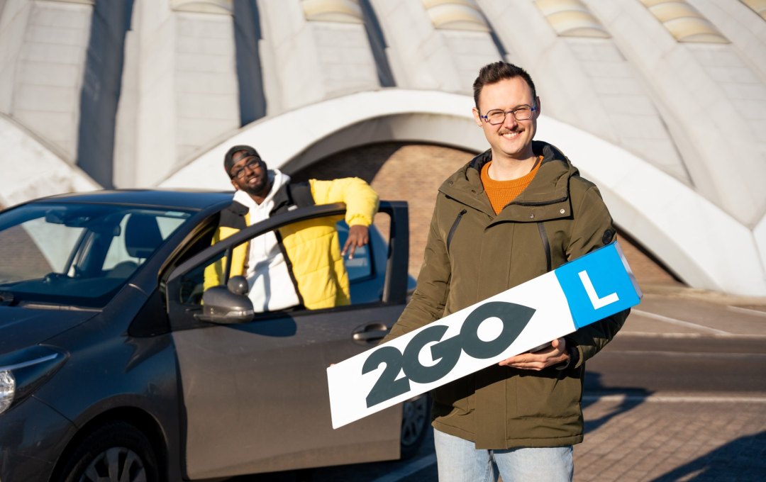 Jeune et buddy conducteur de 2GO Lokeren près du véhicule école